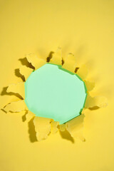 Top view of the hole from ripped yellow paper with a colored background. Mockup. Copy space. Presentation or template. Flat lay