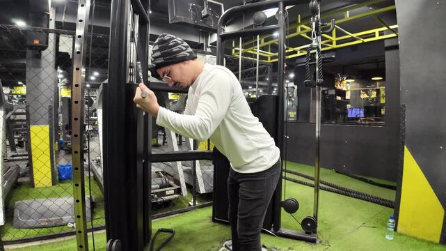  Young Man Performing Triceps Pushdowns with Cable in the Gym, with a Background of Machines and Beautiful Lighting, Captured in Slow Motion