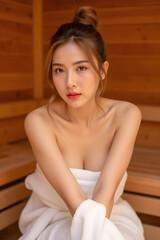 a sexy young asian woman in hot sauna made from wood with white towel