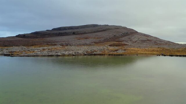 Aerial dolly flying low over a seasonal lake towards Mullaghmore, showcasing ground details.
