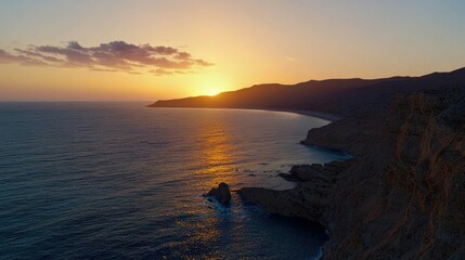Sunset over a coastal landscape with cliffs and ocean waves.