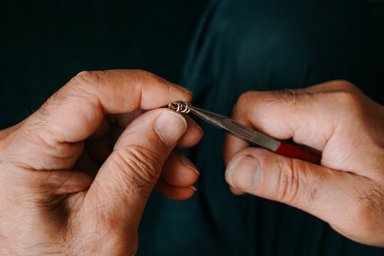 Jeweler making a chain of rings. Close up of the hands of a goldsmith. Concept: jewelry, gold, fashion. Horizontal photo