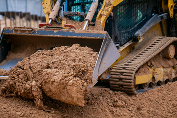 Track compact loader working in construction project leveling the ground and excavating materials...