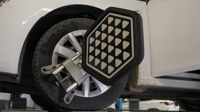 Close-up diagnostics and balancing of wheels on a lift at a modern service station. Collapse of convergence. Checking the wheel balancing on the lifting machine with the help of special equipment.