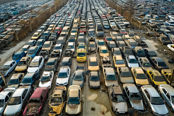 Fototapeta premium An aerial view of abandoned vintage cars in a scrapyard, left to rust and decay over time.