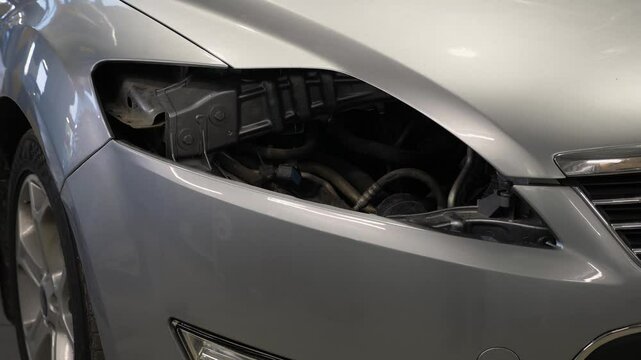 Close-up of a car without a headlight at a service station, replacement of a broken headlight in a modern auto repair shop.