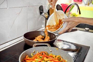 Cooking chicken and vegetables in a home kitchen with colorful utensils and ingredients present