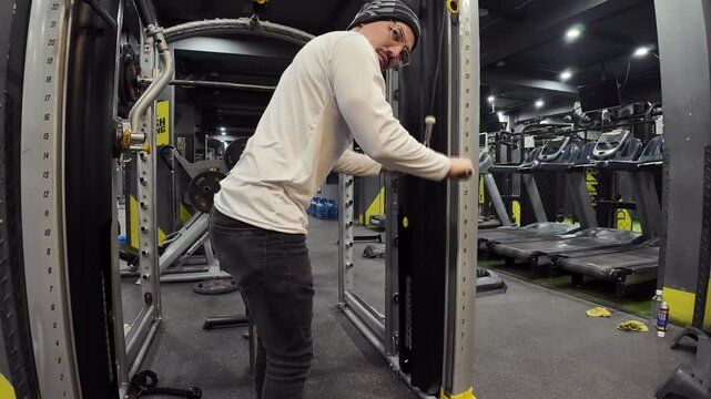 Young Man Performing Triceps Pushdowns with Cable in an Empty Gym, with Treadmills, Maintenance Parts, and Cinematic Lighting