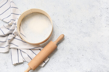 Wooden sieve for flour, rolling pin and napkin on wooden background