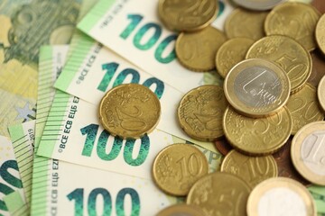 Big amount of euro cent coins lies on hundred euro bills banknotes