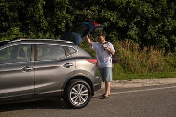 Man with Backpack at Open Car Trunk