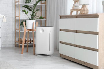 Modern air purifier near commode in living room interior
