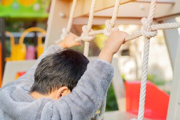 Obraz premium Side view close-up shot of little boy climbing on the playground.