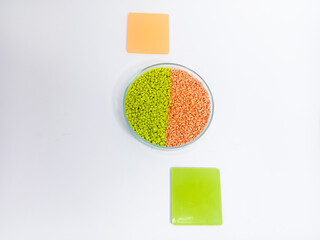 Masterbatch plastic, colorful polymer granules carrying pigments are poured into a glass cup with...