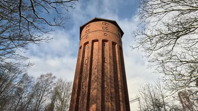 A tall brick water tower on a winter sunny day.