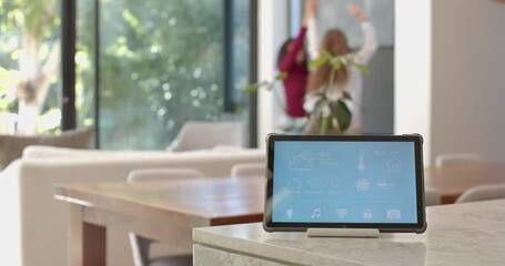 Displaying weather and controls, smart home device with lesbian couple talking in background - Powered by Adobe