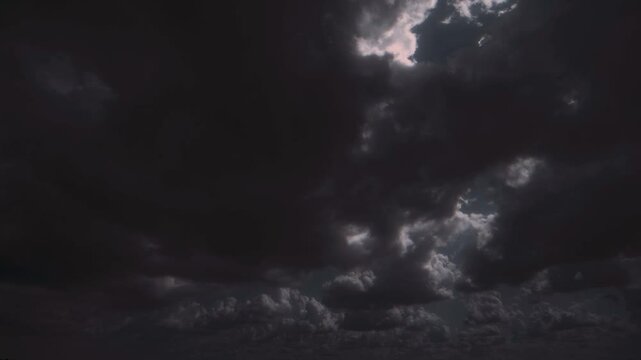 Huge dark storm cloud moving, with internal flashes of light.