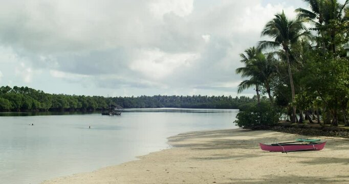 Small boat docked on white sands of Secret Beach in Siargao, Philippines.