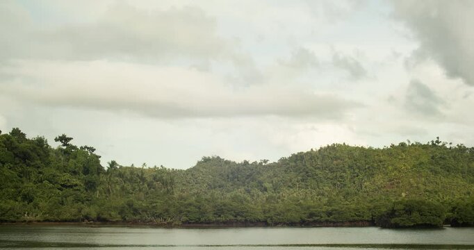 Time-laps of a cloudy day on a mangrove forest and a backdrop of a rainbow in Secret Beach, Siargao.