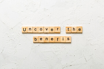 uncover the benefits word written on wood block. uncover the benefits text on table, concept