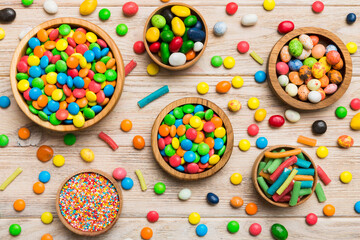 different colored round candy in bowl and jars. Top view of large variety sweets and candies with copy space