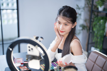 Asia woman beauty influencer makeup artist vlogger live streaming makeup tutorial on smartphone for...