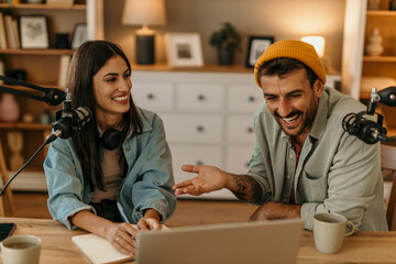 Friendly podcast hosts laughing and exchanging ideas in a professional studio setting