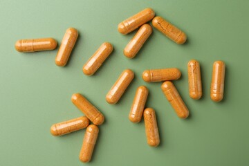 Many turmeric capsules on light green background, flat lay