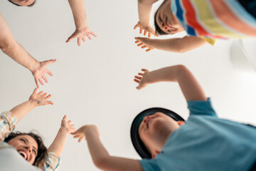 Caucasian family members in casual attire participate in hands stacking activity at home...