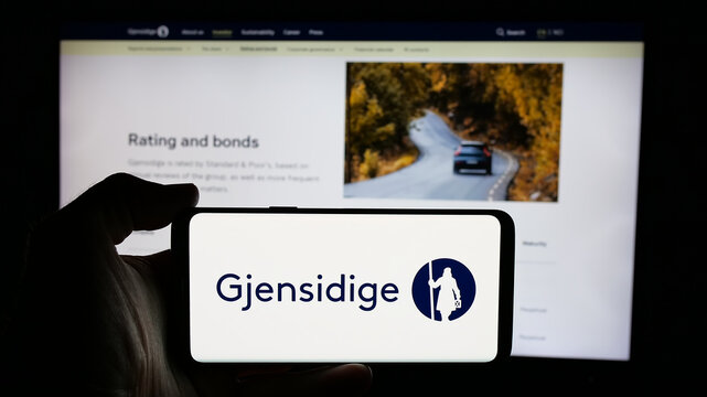 Stuttgart, Germany - 01-14-2025: Person holding cellphone with logo of Norwegian company Gjensidige Forsikring ASA on screen in front of business webpage. Focus on phone display.