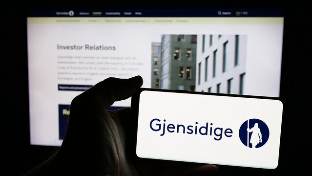 Stuttgart, Germany - 01-14-2025: Person holding mobile phone with logo of Norwegian company Gjensidige Forsikring ASA on screen in front of web page. Focus on phone display.