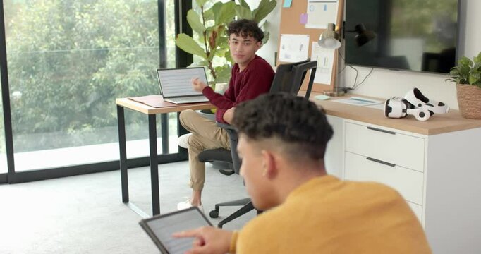 Using tablets, multiracial gay couple working in home office setting