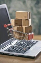 A miniature shopping cart with boxes on top, sitting atop an open laptop computer.