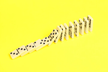 Domino effect. Tiles falling on yellow background