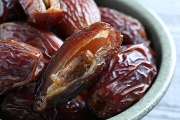 Many tasty dried dates in bowl on table, closeup