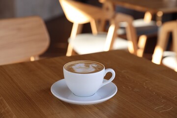 Cup of aromatic coffee on wooden table in cafe