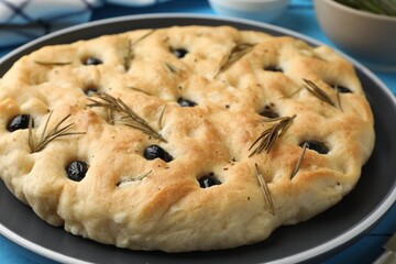 Delicious focaccia bread with olives and rosemary on table, closeup