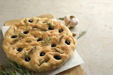 Delicious focaccia bread with olives, rosemary and garlic on grey table, closeup. Space for text