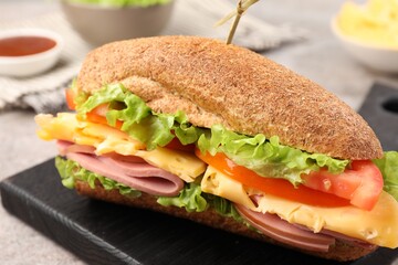 Delicious baguette sandwich with ham on grey table, closeup