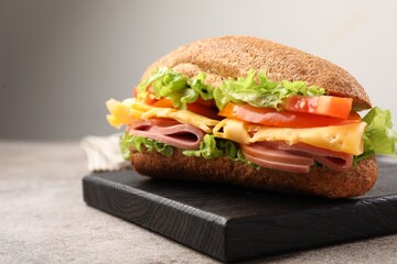 Delicious baguette sandwich with ham on grey table, closeup