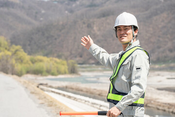 河川敷・堤防で交通整理をする男性ガードマン
