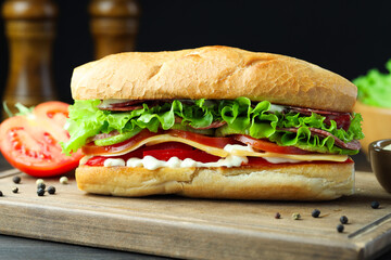 Delicious baguette sandwich with salami and cheese on table, closeup