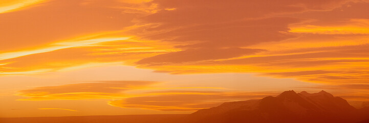 Fototapeta premium Golden sky at sunset with mountain silhouettes in South Iceland's serene landscape