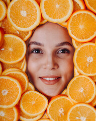 young beautiful caucasian woman portrait, pretty smiling girl face surrounded by bright round orange slices, fashion portrait