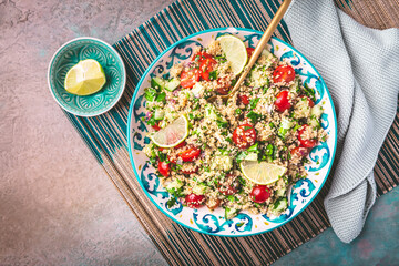 A bowl of fresh tabbouleh salad with chopped tomatoes, cucumbers, and parsley