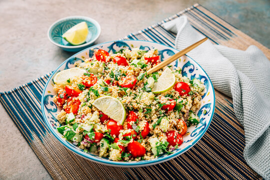 A bowl of fresh tabbouleh salad with chopped tomatoes, cucumbers, and parsley