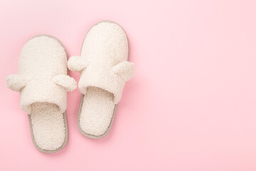 Soft teddy slippers on color background, top view