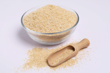 Oat bran in glass bowl and wooden scoop on white background