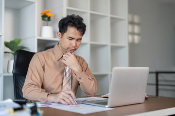 Obraz premium Businessman deep in thought while analyzing data on laptop in office