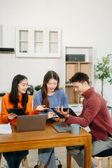 Teamwork and creativity with young adults collaborating on laptops and tablets in a cozy workspace.